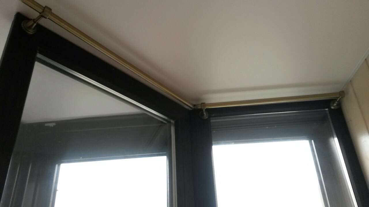 Карниз для штор с шарнирами на кронштейнах к оконной раме под натяжным потолком на балконе.
